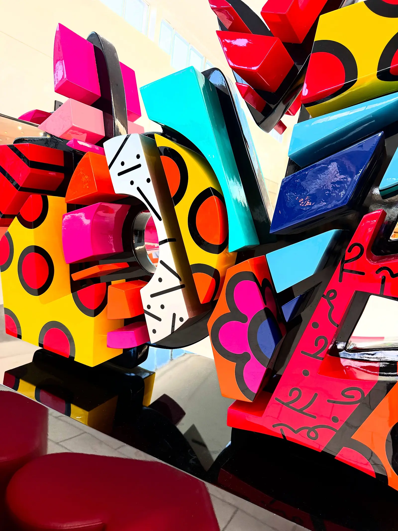A heart sculpture painted in pink, orange, blue and gold, photographed close up.