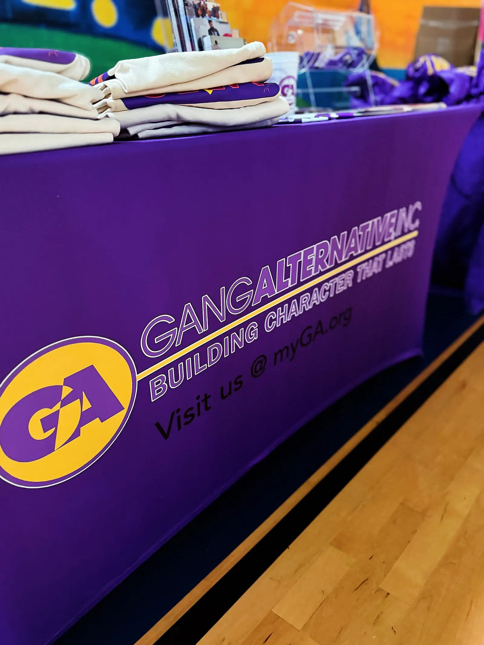 Folded shirts stacked on a table in front of a partner organization's banner.