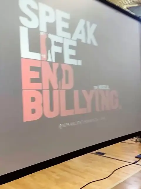 A projection screen reading Speak Life, End Bullying in a school gymnasium.
