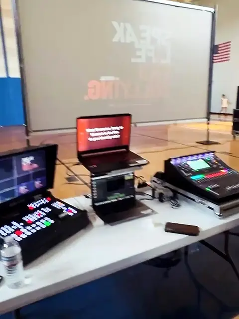 A table with a monitor, console and controller set up in a youth club room.