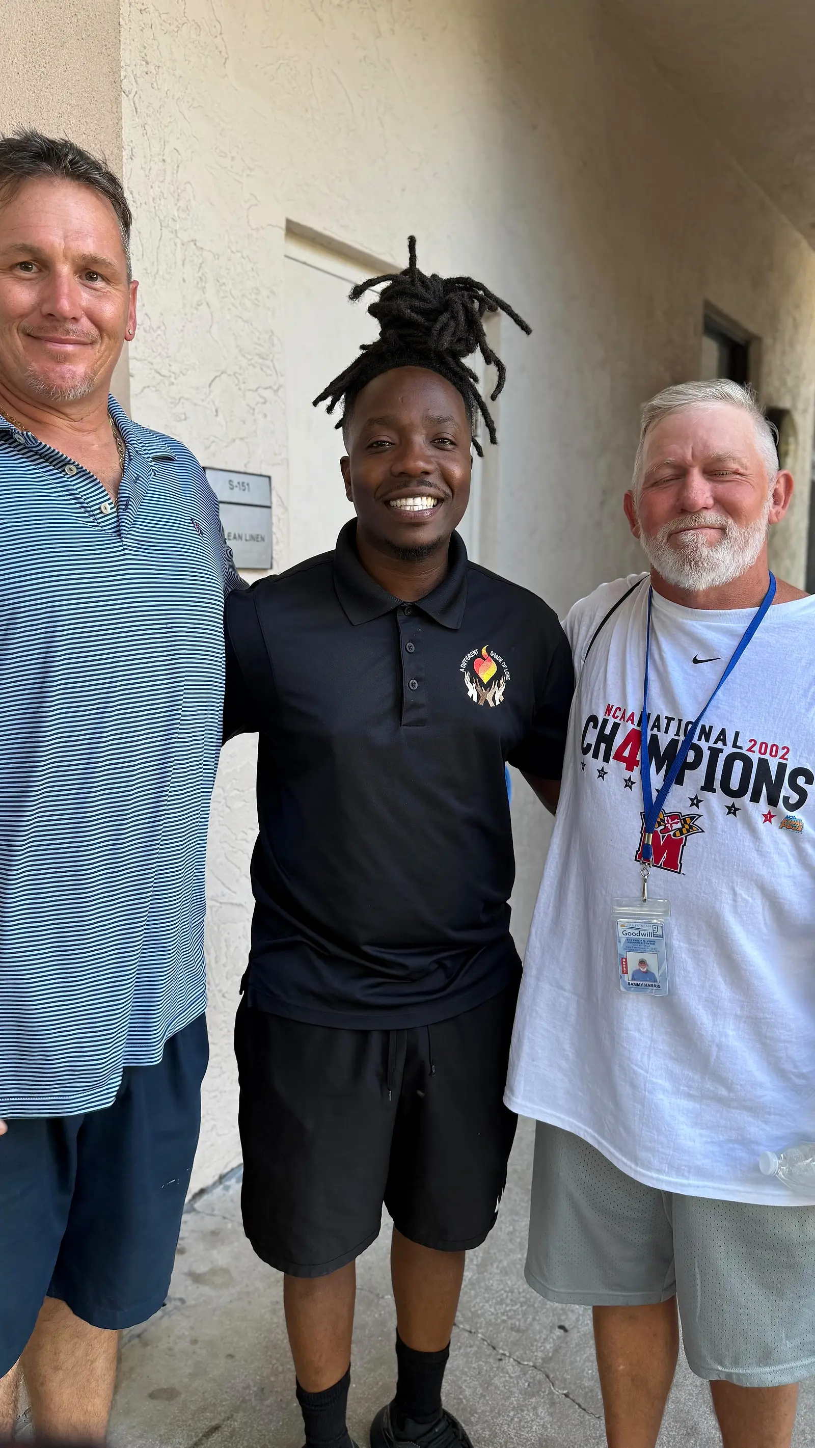Three people standing together and smiling, photographed at a shelter visit.