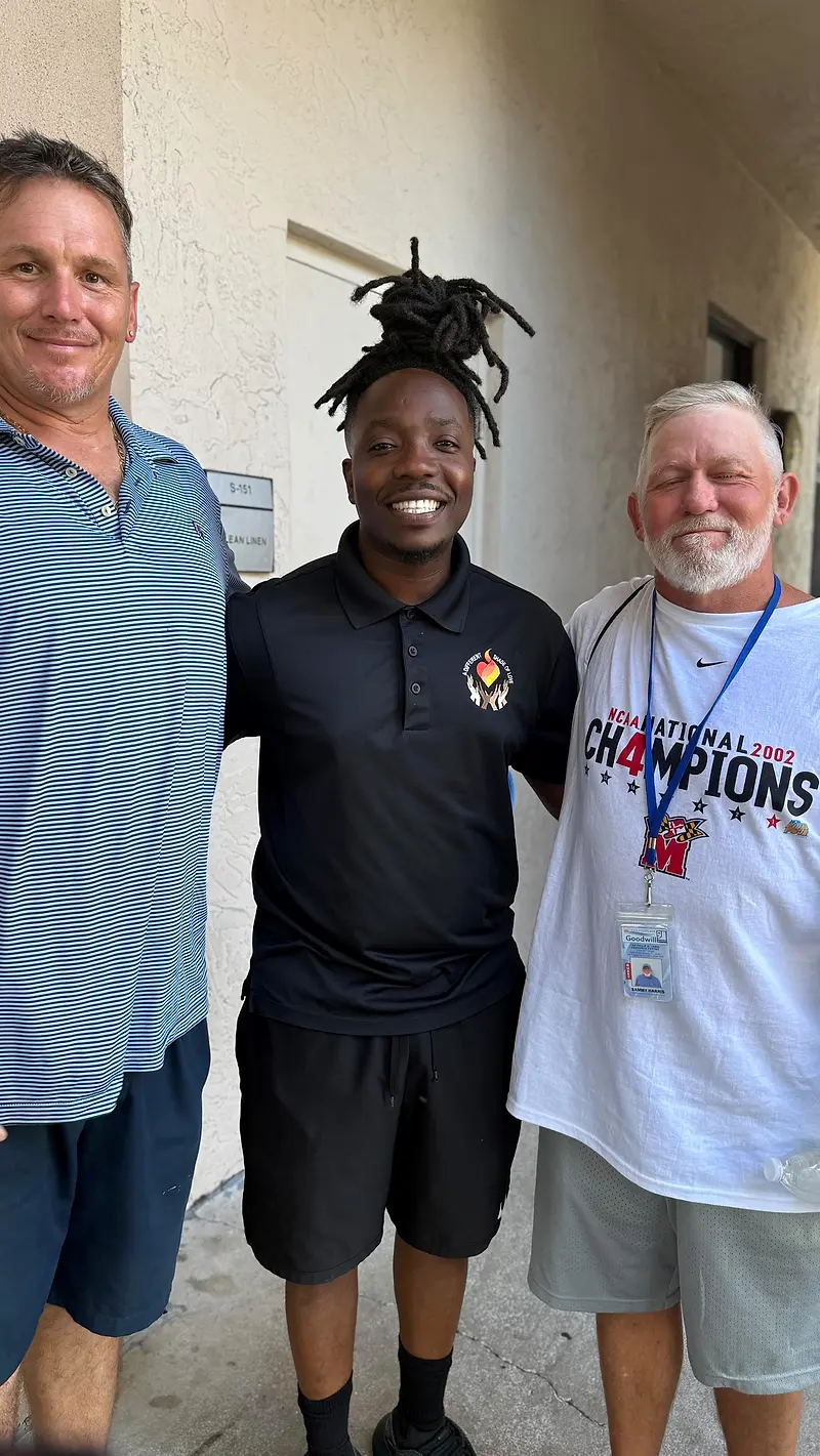 Francky Pierre-Paul standing between two men outside a building, all three facing the camera.
