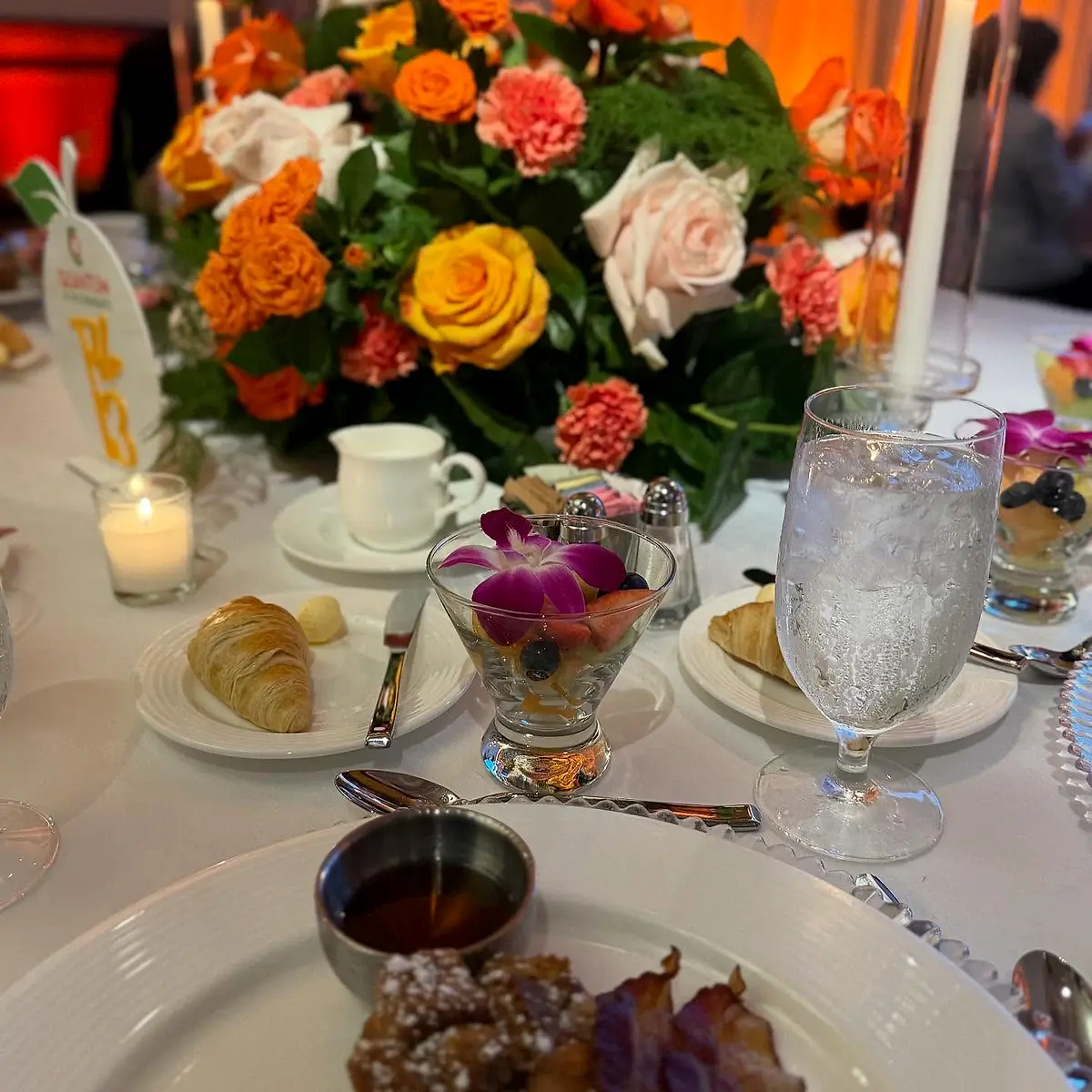 A close view of a table centerpiece with orange roses and iced drinks.