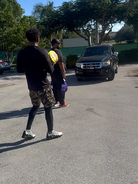 A car parked on a residential street with two people standing beside it.
